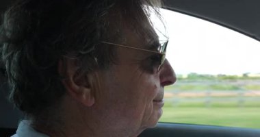 Senior man wearing sunglasses driving on road