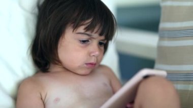 Akıllı telefonla medya içeriğini izleyen tatlı bir bebek. Küçük çocuk film tarafından hipnotize edildi.