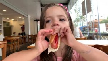 Little girl eating hot dog meal