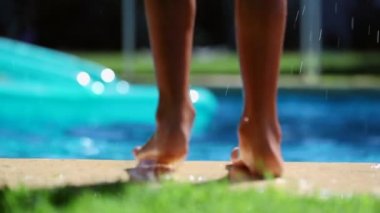 Yüzme havuzunun kenarındaki çocuk ayakları suya atlıyor