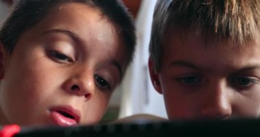 İki kardeş kontrolörle oyun oynuyor. Kardeş izliyor ve kardeş ekranını paylaşıyor.