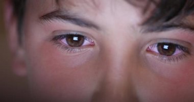 Boy eyes looking at screen device, blue light glowing from tablet screen. Child macro eye