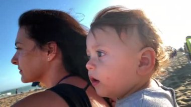 Mother and baby infant together at beach during summer day