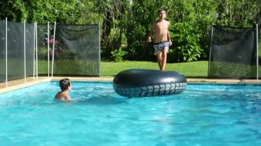 Güneşli bir günde evin arka bahçesinde havuzda eğlenen iki kardeş.