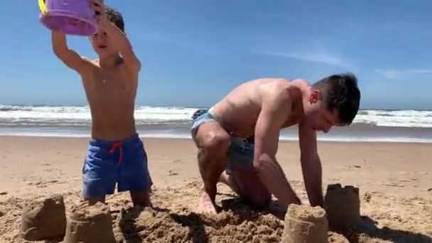 ビーチビルの城で家族 砂城を作る息子と父 — ストック動画
