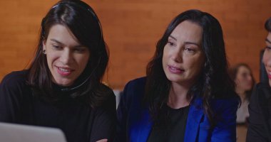 Çağrı merkezindeki bilgisayarların önünde genç personele koçluk yapan kadın yönetici. Geceleri ofis işyerinde çalışan üç kadın işçi iş hakkında konuşuyor.