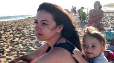 Anne ve bebek sahilde birlikte dinleniyorlar.