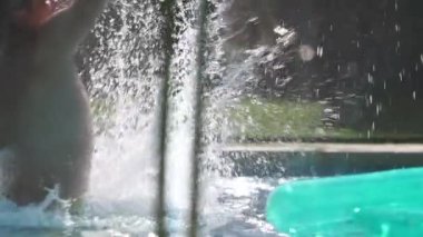 Babası çocuğu havuza yavaş çekimde fırlatıyor.