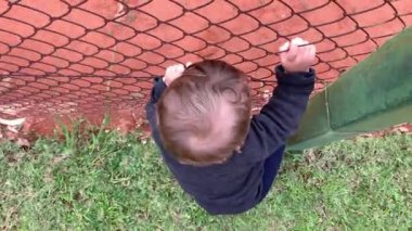 Bebek çitlere tutunup maç seyrediyor.