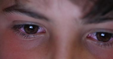 Boy macro eyes staring at screen device at night. Child browsing internet eye close-up