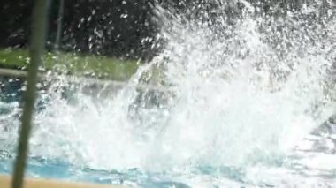Çocuk havuza yavaş çekimde su sıçratıyor.