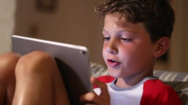 Çocuk tablet aygıtı kullanıyor. Genç bir çocuk aletin teknoloji ekranına bakıyor.