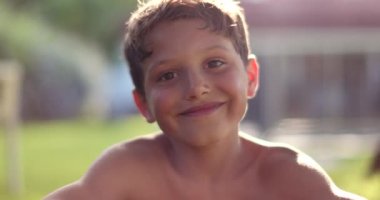 Handsome child boy smiling to camera in outdoor backyard garden. Happy kid portrait