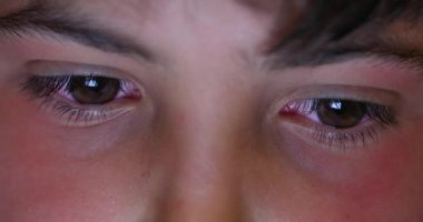 Genç oğlanın gözleri gece ekrana bakıyor. Tablet aygıtına bakan çocuk yüzünü kapat