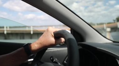 Yolda araba kullanan kişi, kırsal kesimde direksiyon tutarken yakın plan.