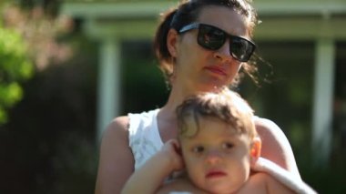 Mother holding adorable baby toddler wrapped with towel after pool