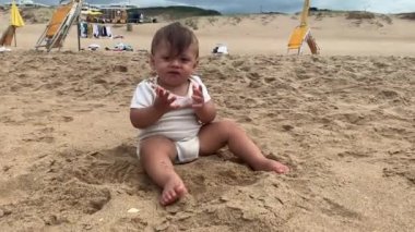 Kumsalda kum yiyen bebek, ağzına kum koyan bebek.