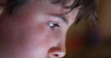 Boy eyes looking at device screen. Child staring at bright blue display closeup face