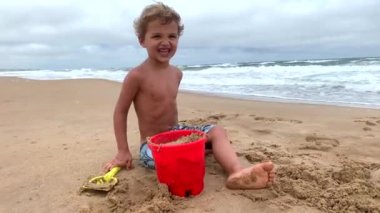 Küçük çocuk sahilde gülüyor, çocuk kıyıya gülümsüyor mutlu oluyor.