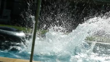 Çocuk havuzda eğleniyor, çocuk ağır çekimde havuza atlıyor ve koşuyor.