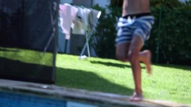 Yüzme havuzuna yavaş çekim 120 fp hızla koşan eğlenceli genç çocuk.