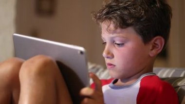 Young boy using tablet device, kid face reacting to video-game. Child staring to screen