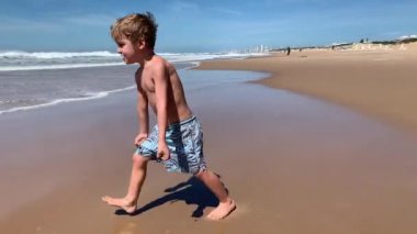 Mutlu çocuk plajda zıplıyor ve kendinden geçiyor.