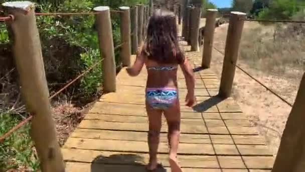 ビーチで木道を歩く子供の女の子 — ストック動画