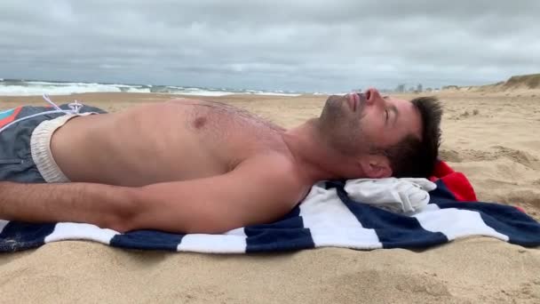 男子在海滩日光浴 眼睛闭着 在海滨放松的人 — 图库视频影像