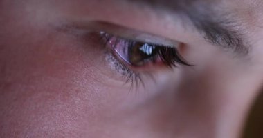 Boy closeup eye watching content online. Child macro eyes close-up staring and looking at tablet screen at night