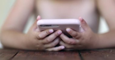 Bebek elleri akıllı telefonu yakından tutuyor. Bebek eli cep telefonuna bakıyor.