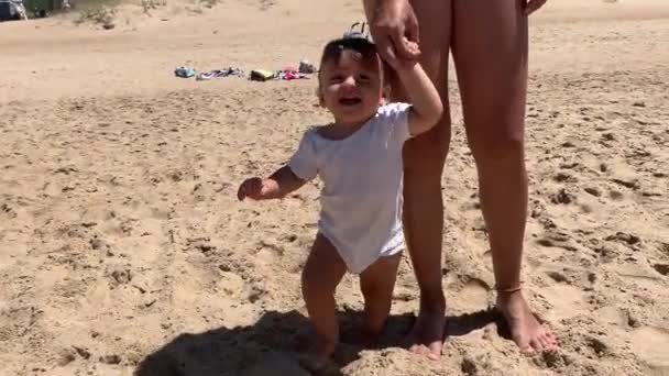 ビーチで赤ちゃんを抱えている母親 幼児男の子歩くことを学ぶ 赤ちゃんの最初のステップ — ストック動画