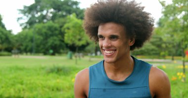 African young black man walking at park smiling feeling happy