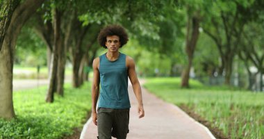 African man walking at green park path surrounded by nature