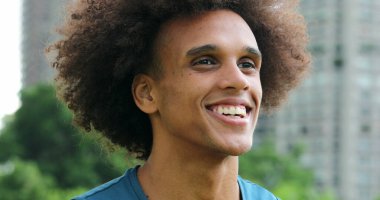 African man closing and opening eyes in meditation outside, smiling and feeling joy and peace