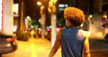 Back Young black african man walking in city at night when raining, downtown