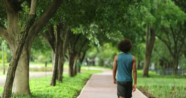 Back of african black man walking in nature pathway park