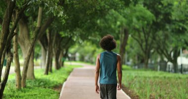 Back of african black man walking in nature pathway park