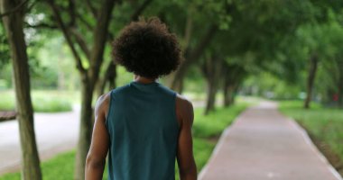 Back of african black man walking in nature pathway park