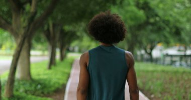 Back of african black man walking in nature pathway park