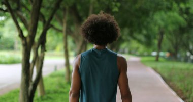 Back of african black man walking in nature pathway park