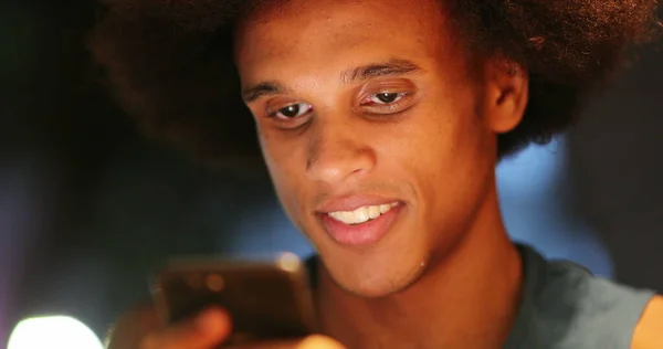 Casual real life laugh and smile of african american black man in front of cellphone screen device