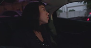 Young woman in car backseat stuck in traffic at night commuting from work. Anxious passenger with worried emotion feeling overwhelmed by modern life