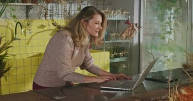 Businesswoman using laptop managing online orders. Female small business entrepreneur in front of computer using modern technology browsing internet