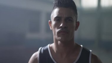 Spor giyimli Güney Amerikalı bir adamın portresi. Ciddi bir ifadeyle dramatik ışıklandırmayla kameraya bakıyor.