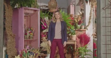 Businesswoman owner of local flower store standing in front of business. Portrait of a female entrepreneur smiling at camera