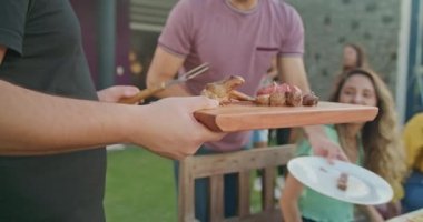 Bir grup arkadaş evin arka bahçesindeki barbekü partisinde sohbet ediyorlar. Masada oturan herkes gülüyor ve mutlu..