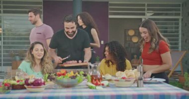 Bir grup arkadaş evin arka bahçesindeki barbekü partisinde sohbet ediyorlar. Masada oturan herkes gülüyor ve mutlu..