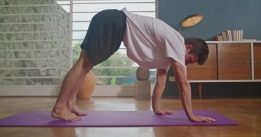 Person practicing yoga at home. Man stretching body exercising in living room interior