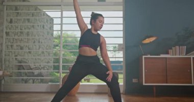 Woman training yoga at home with online instructor with tablet. Girl stretching and exercising at in living room